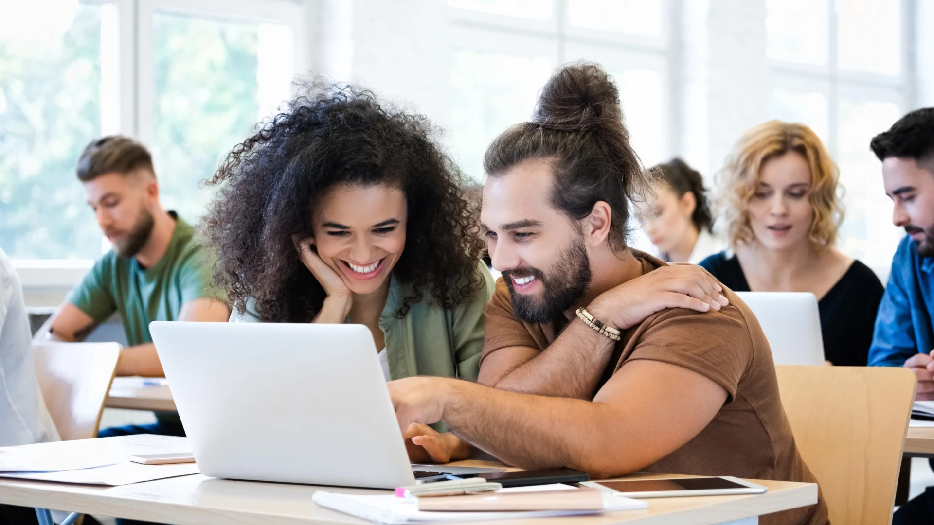 Estudantes universitários sorridentes colaborando em um projeto no notebook em sala de aula