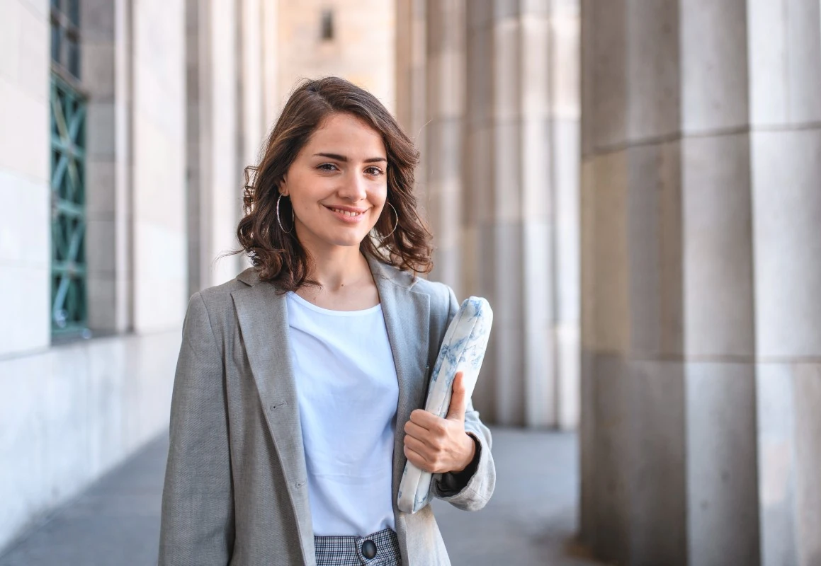 Estudante universitária confiante posando com material de estudo em um ambiente acadêmico inspirador e profissional