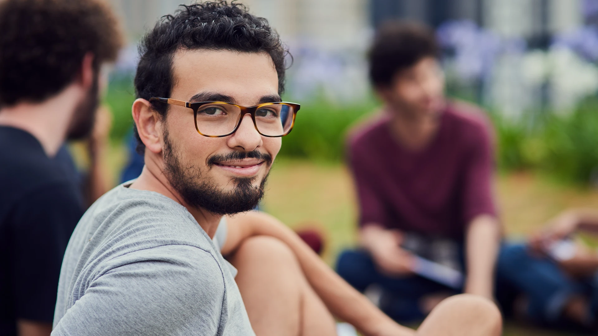 Estudante universitário feliz posando para foto em um ambiente acadêmico descontraído ao ar livre