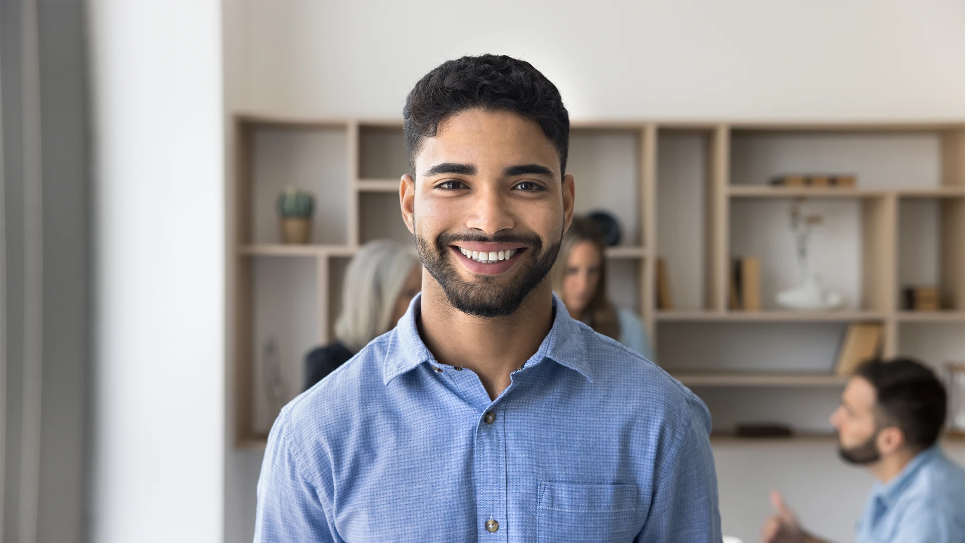 Jovem profissional sorridente em um escritório moderno com colegas ao fundo