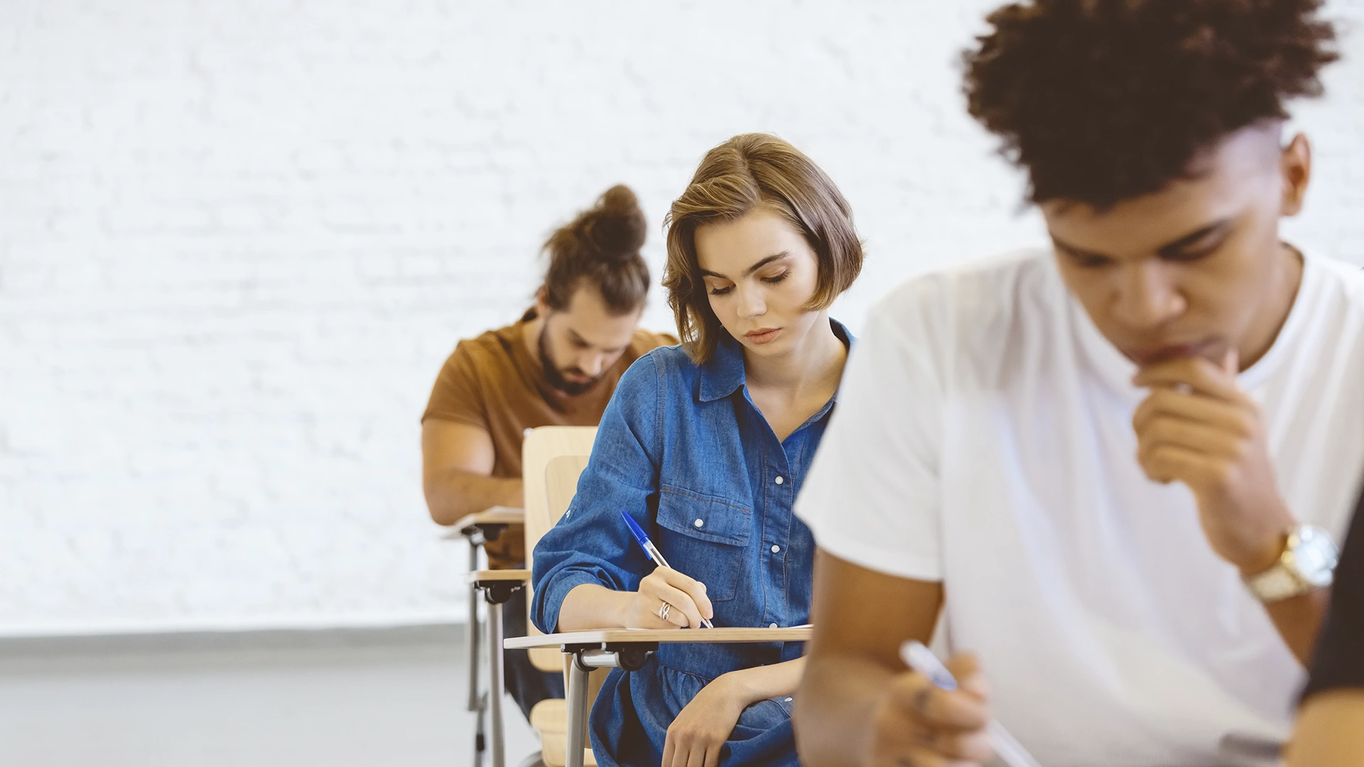 Estudantes focados realizando uma prova ou exercício em uma sala de aula moderna