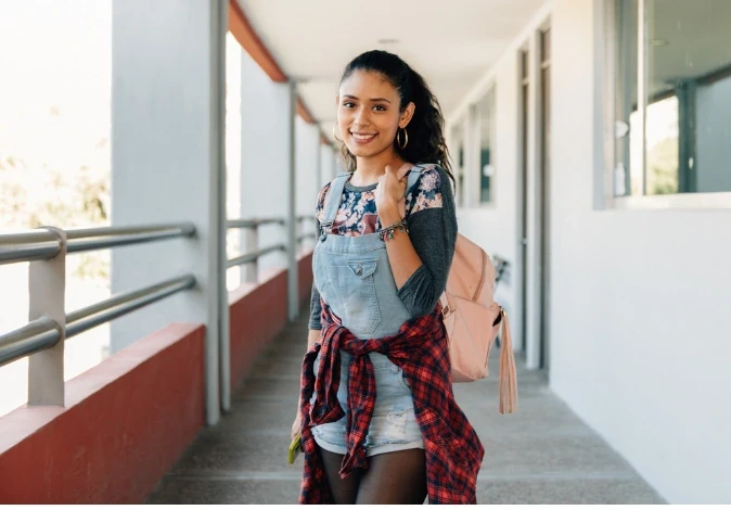 Estudante universitária sorridente caminhando no corredor da faculdade