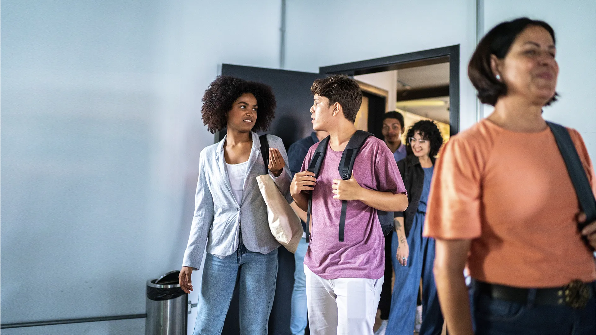 Estudantes universitários conversando e caminhando em um corredor escolar