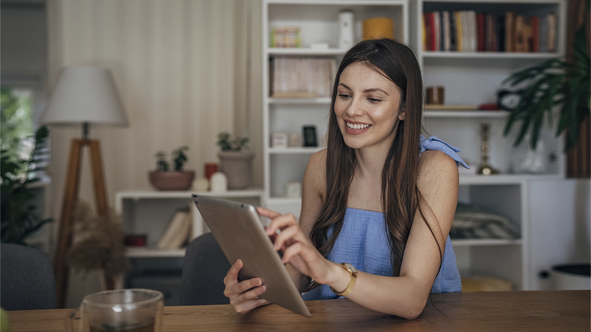 Jovem mulher sorridente usando tablet digital em casa para estudar ou trabalhar