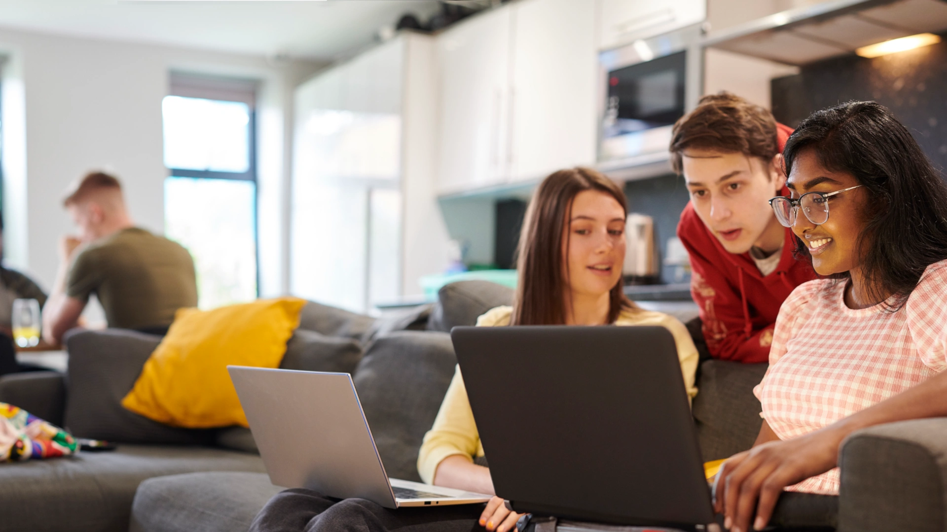 Estudantes universitários colaborando em projetos acadêmicos usando laptops em um ambiente de estudo compartilhado e moderno