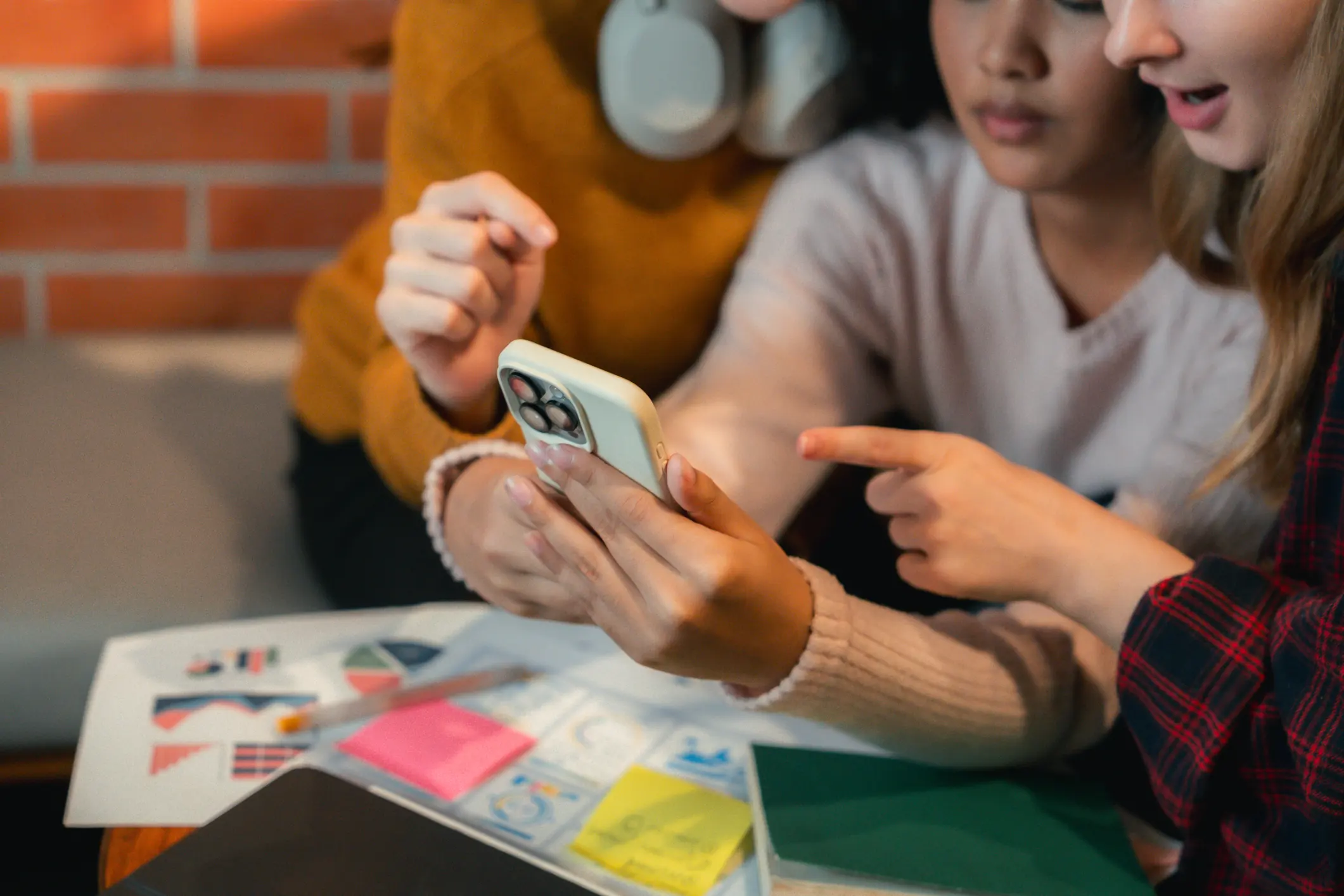 Grupo de estudantes universitárias colaborando em um projeto acadêmico usando um smartphone Estudantes universitárias analisando dados e colaborando em um projeto de pesquisa acadêmica com tecnologia