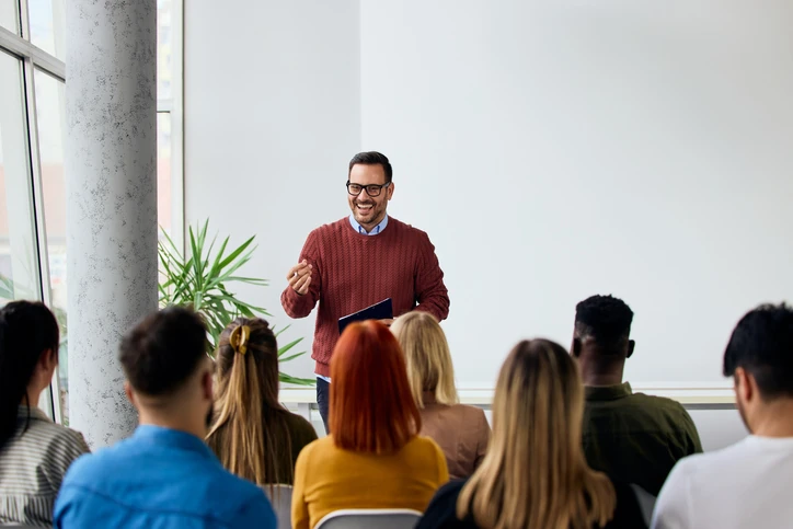 Professor engajado realizando palestra ou aula interativa para grupo diversificado de estudantes em ambiente acadêmico moderno