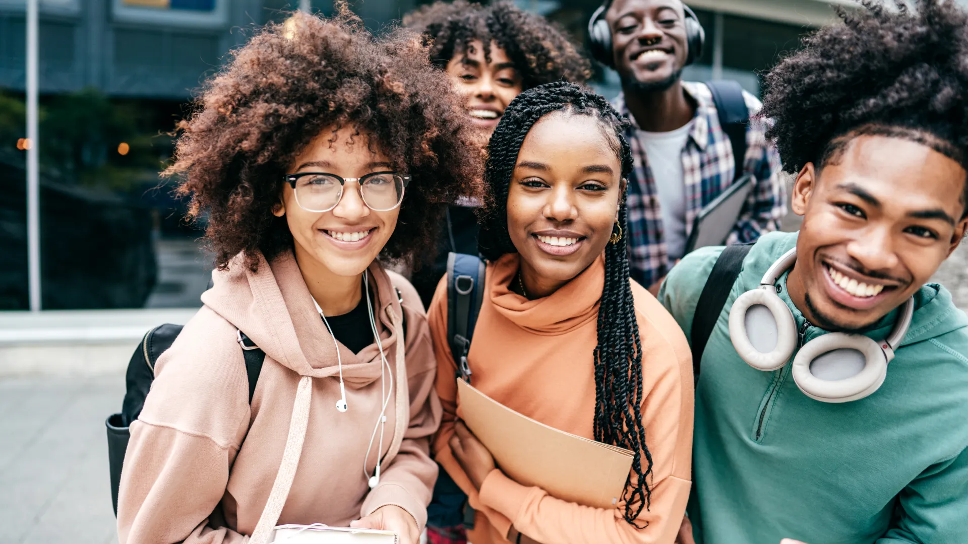 Estudantes universitários jovens e diversificados posando juntos em um campus universitário moderno para representar a vida acadêmica