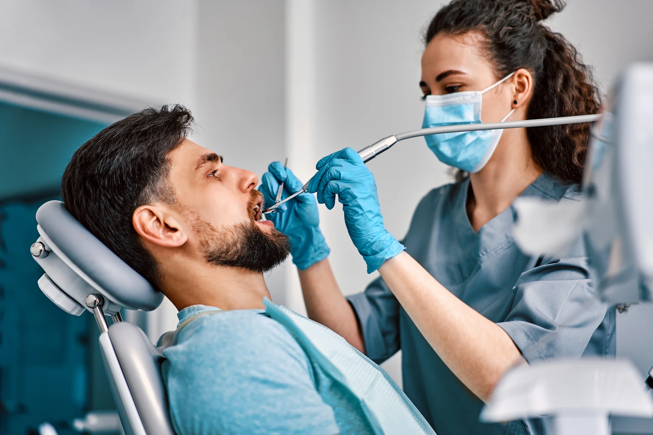 Dentista realizando procedimento odontológico em paciente no consultório