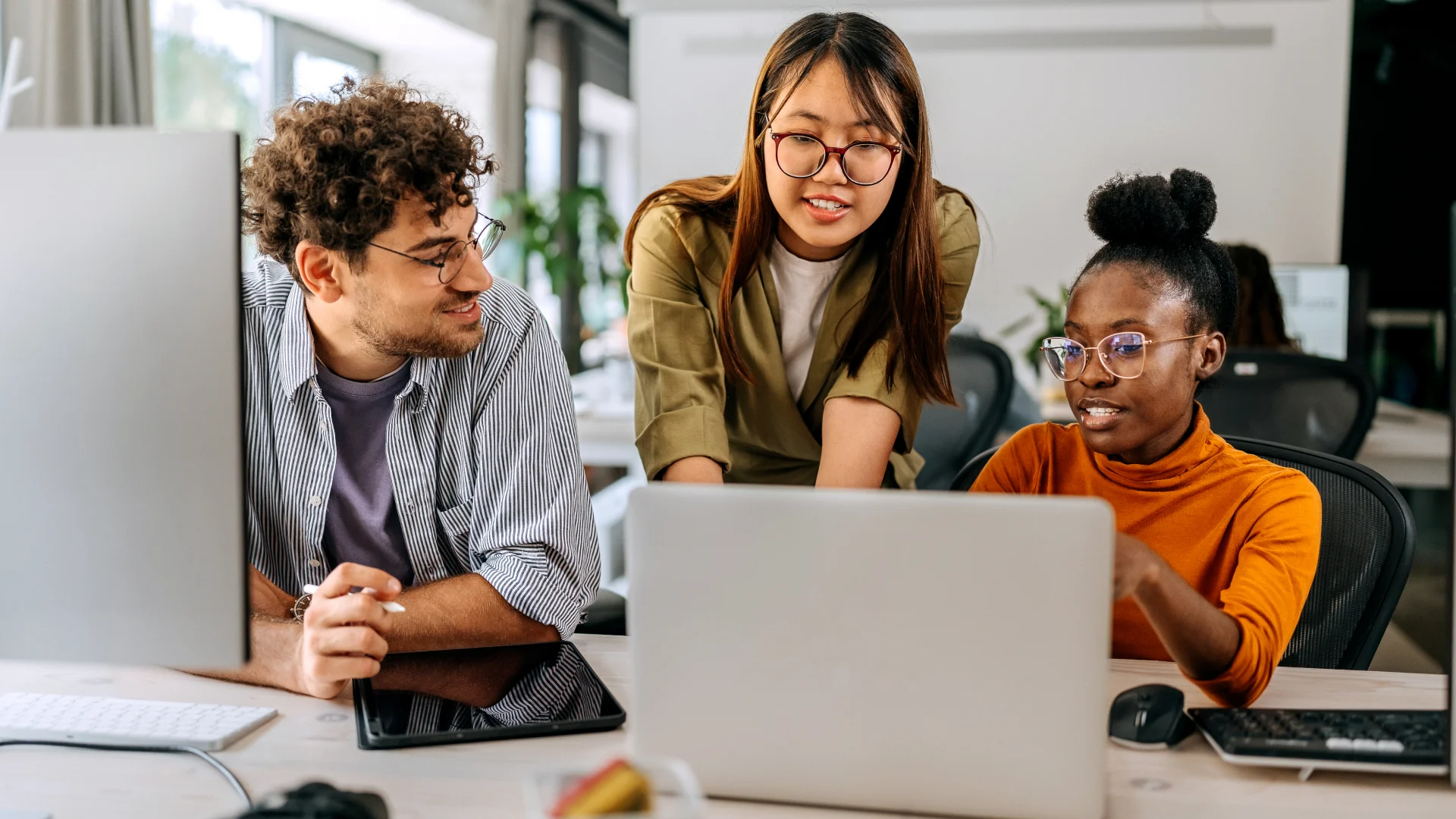Equipe de jovens profissionais trabalhando juntos em um projeto colaborativo utilizando laptops no ambiente de escritório moderno