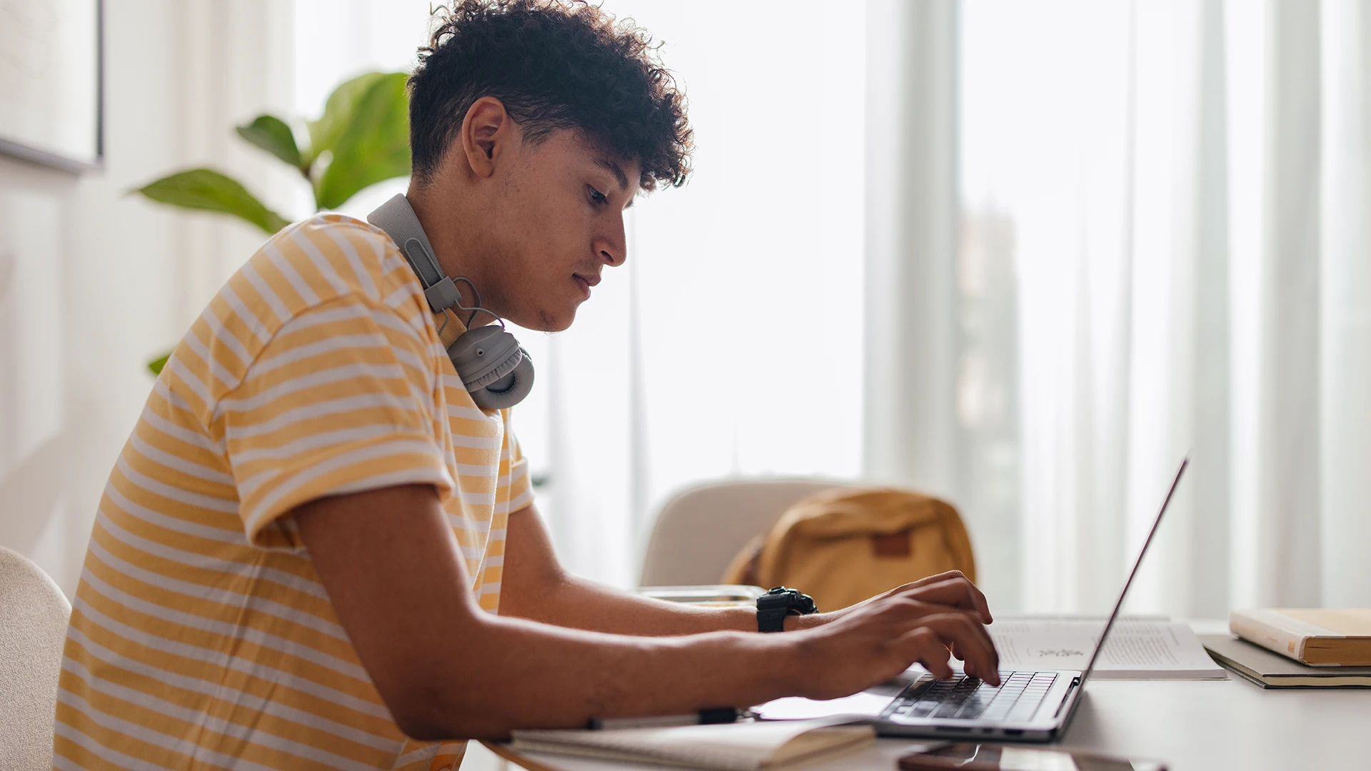 Estudante jovem usando laptop para estudar em casa com fones de ouvido