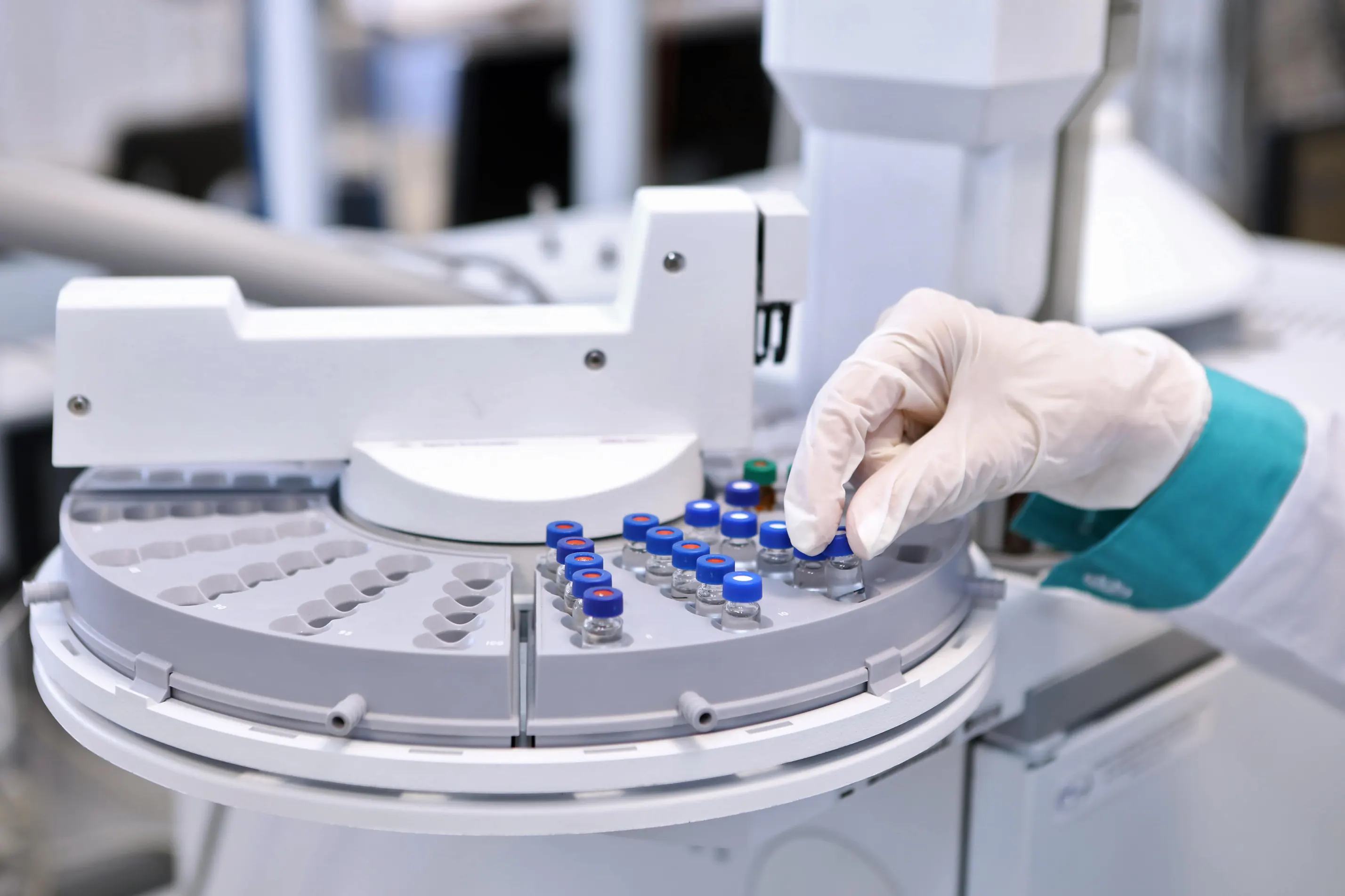 Pesquisador manipulando frascos de amostra em equipamento de cromatografia de laboratório