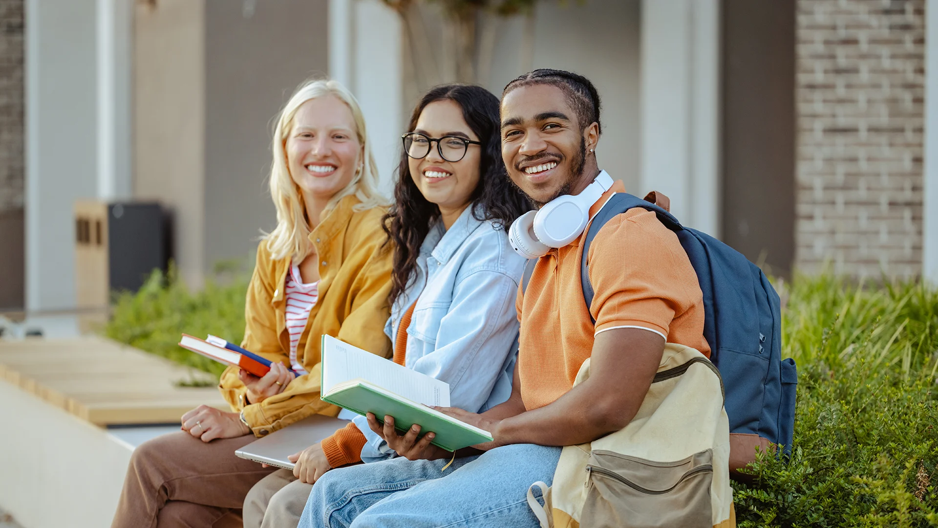 Grupo de estudantes diversos sentados ao ar livre estudando com livros e mochila