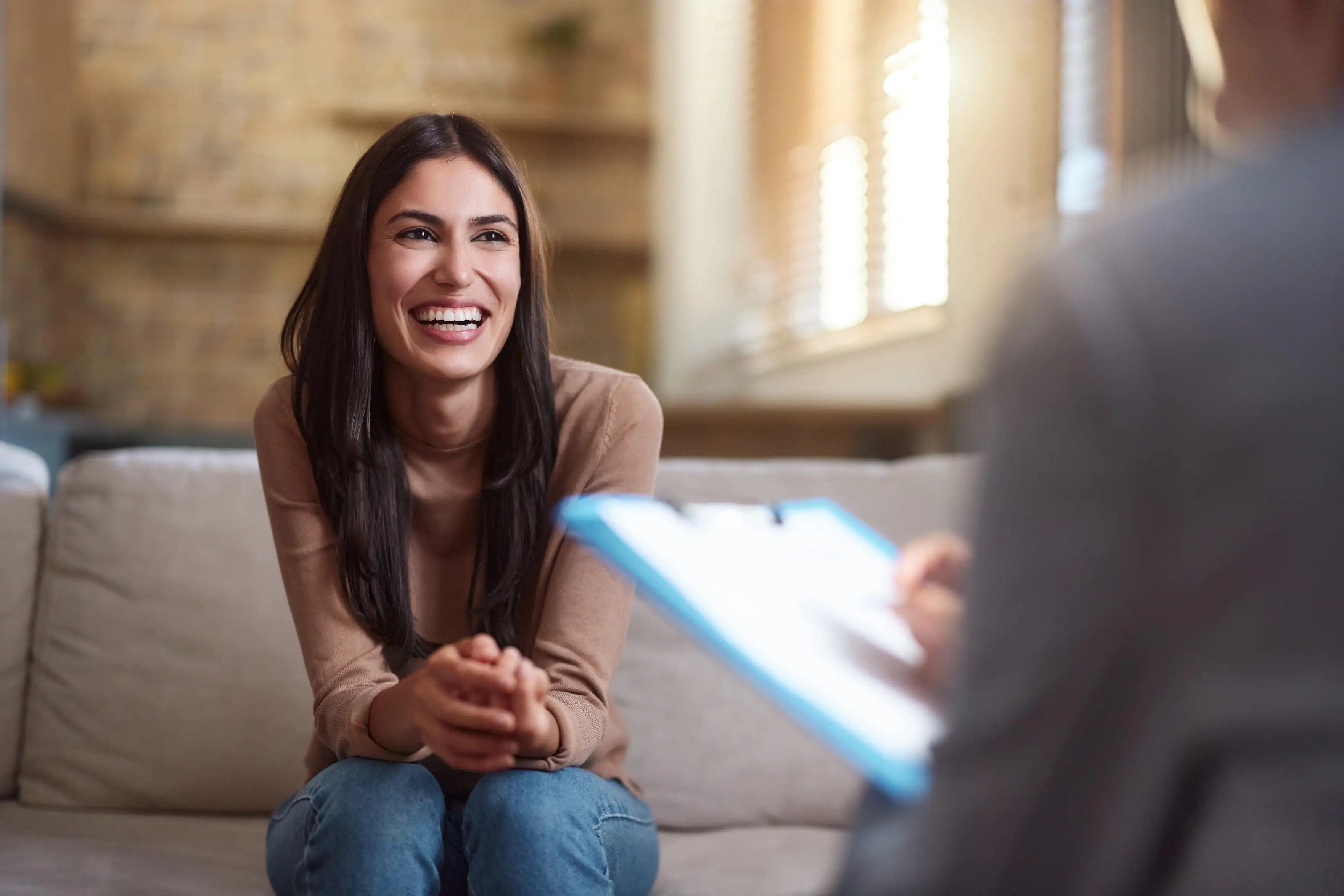 Paciente jovem e feliz conversando com terapeuta durante uma consulta de psicologia em ambiente acolhedor