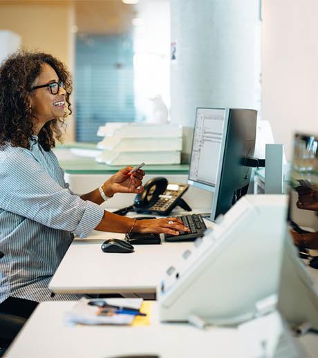 Profissional feminina sorridente utilizando computador e cartão de crédito em um ambiente de escritório corporativo