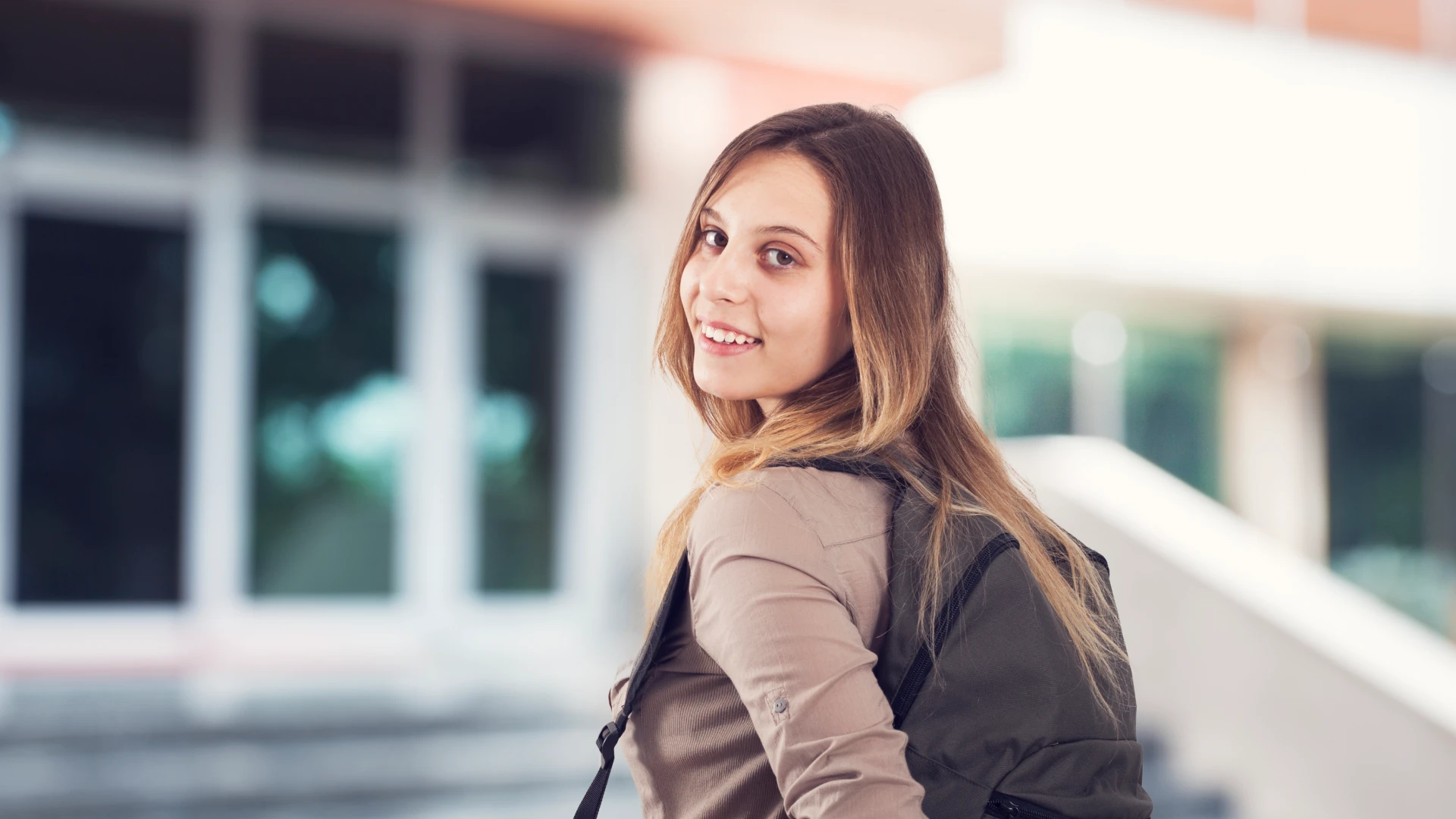 Estudante universitária feliz caminhando pelo campus preparada para as aulas com sua mochila escolar