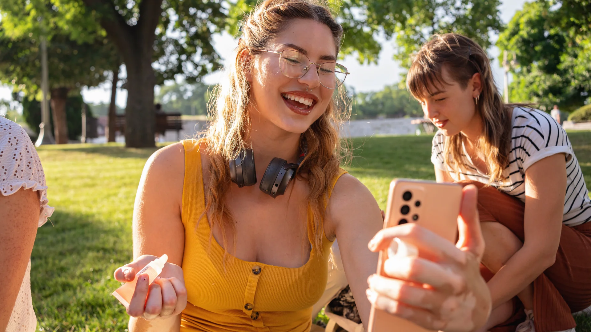Grupo de amigas jovens se divertindo e tirando fotos com smartphone em um dia ensolarado ao ar livre