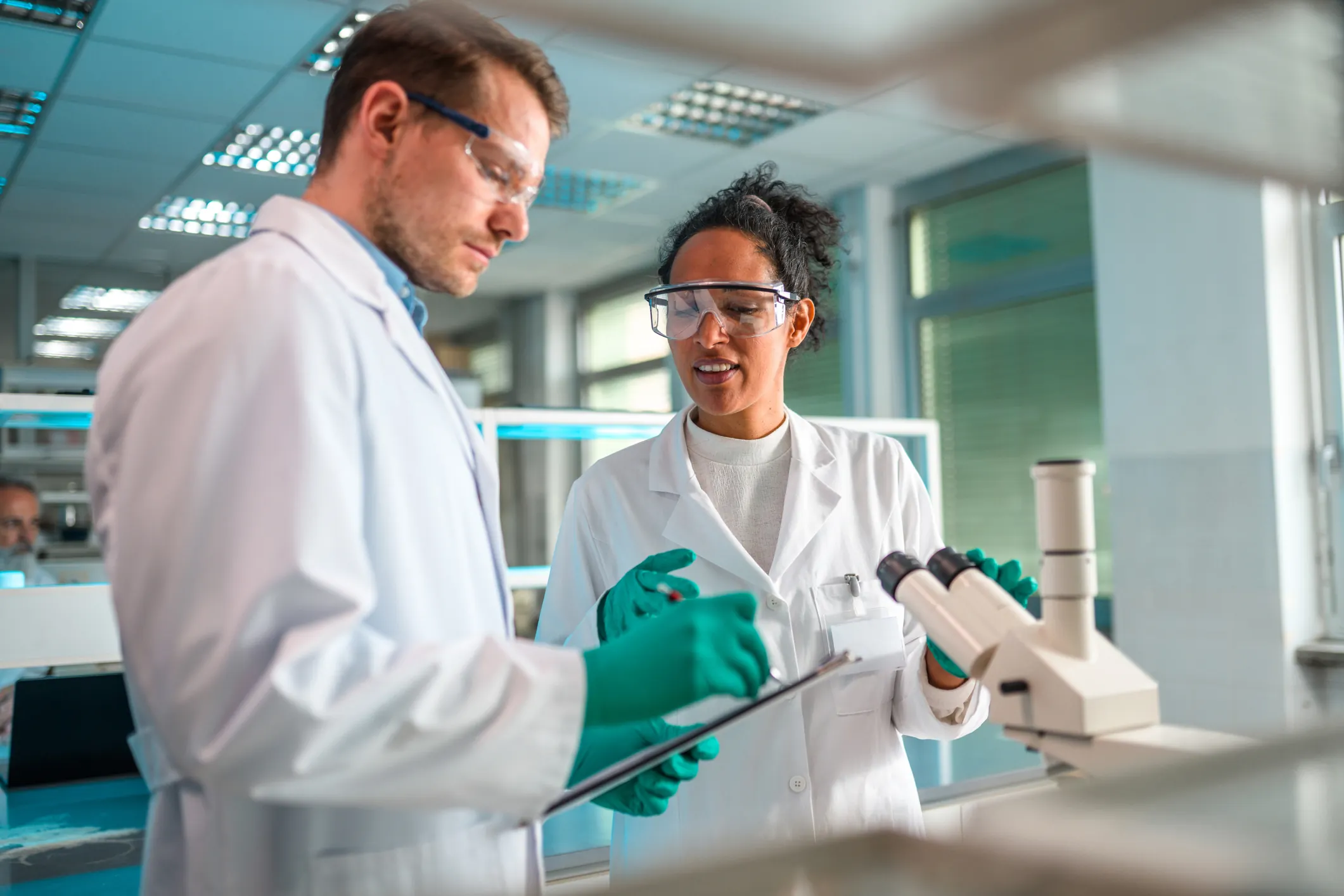 Cientistas trabalhando em laboratório com microscópio e prancheta