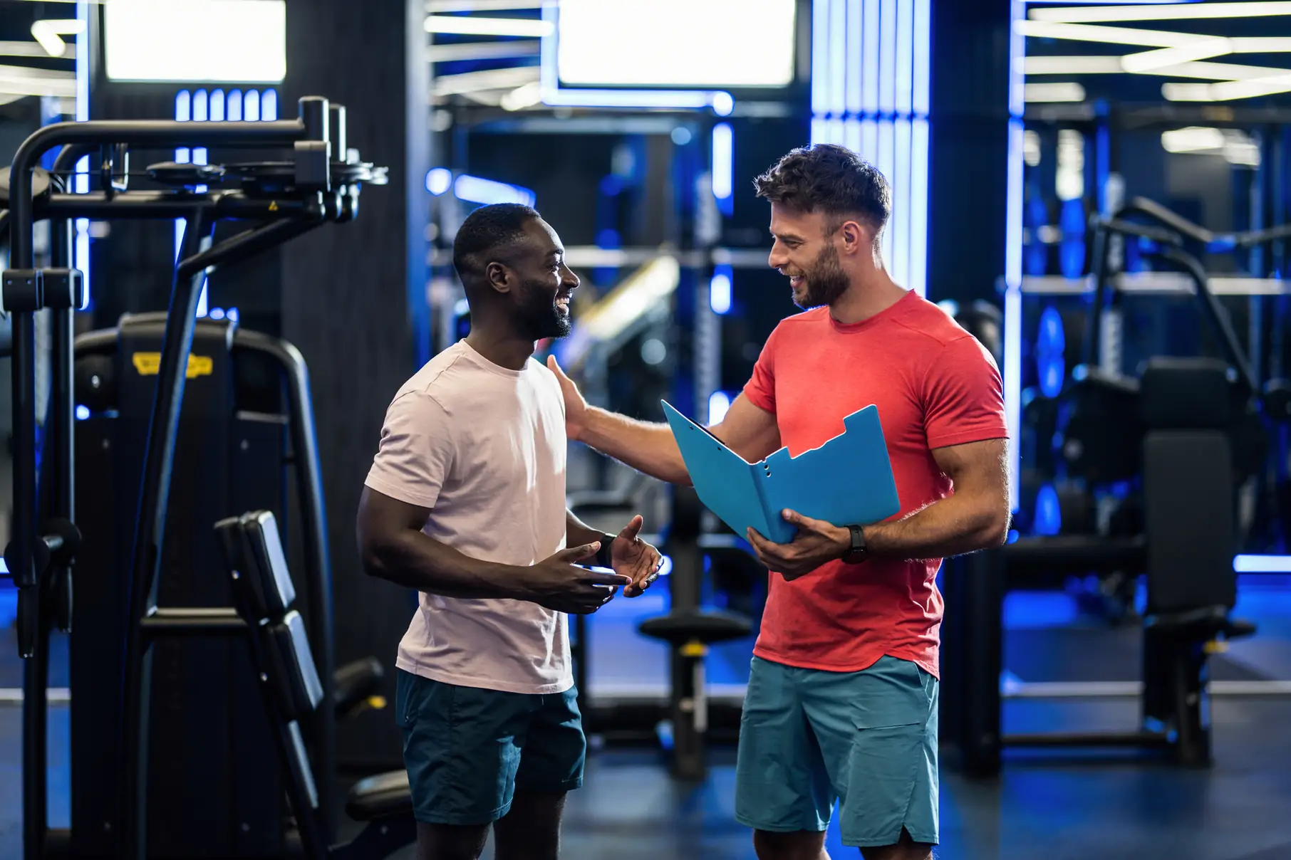 Personal trainer conversando com aluno em uma academia moderna