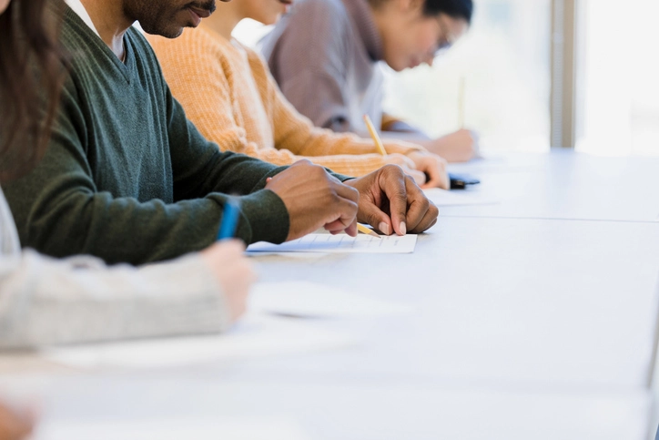 Grupo de estudantes universitários concentrados realizando uma prova em sala de aula