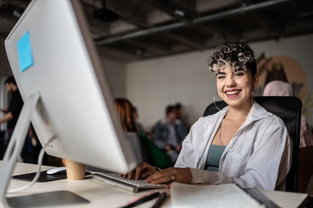 https://estaticos.animaeducacao.com.br/medias/89f9b834-3079-4b7d-a1ea-e7ea41547a0e.webp Estudante ou profissional feliz trabalhando em um ambiente de escritório colaborativo e moderno