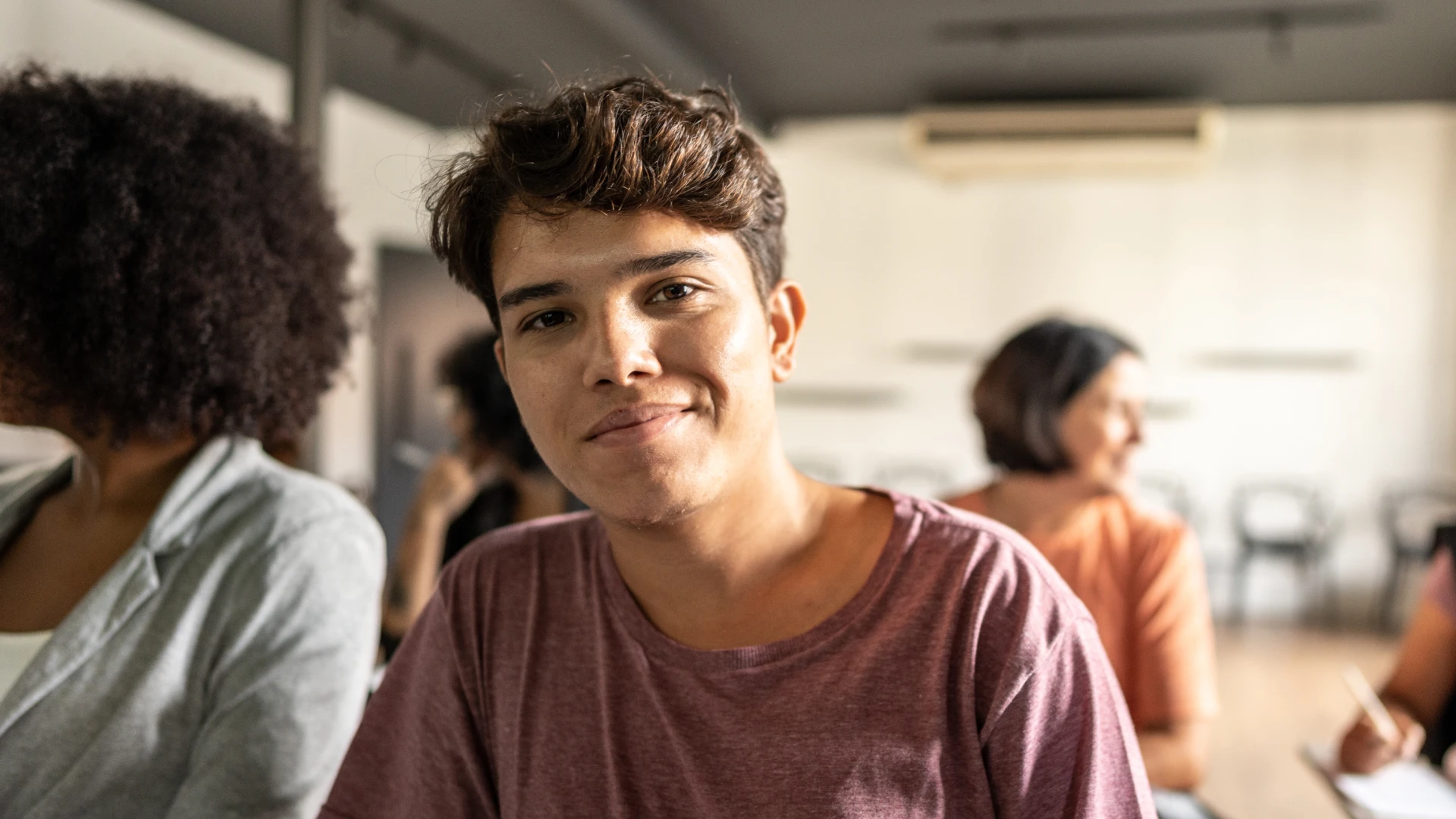 Jovem estudante universitário sorrindo durante aula em ambiente de aprendizagem colaborativa e moderna