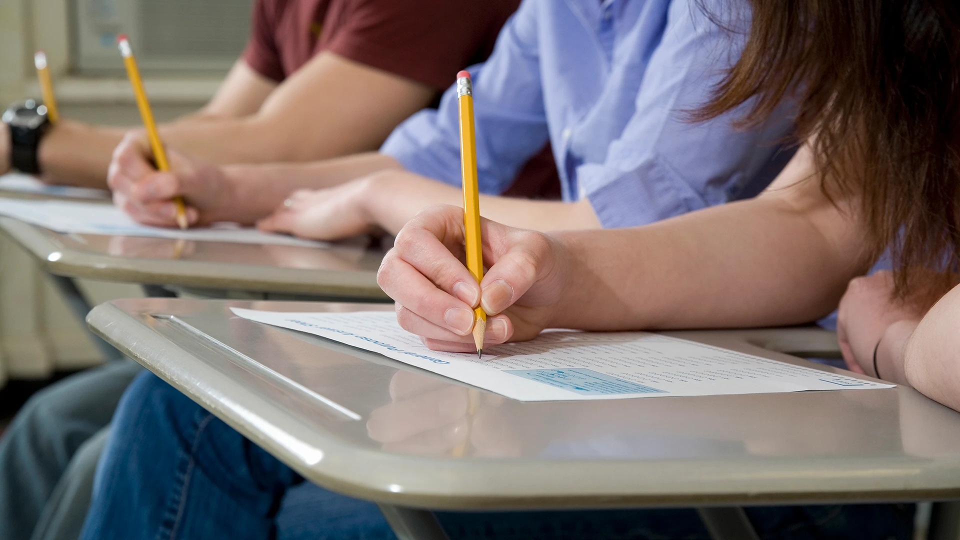 Estudantes concentrados realizando uma prova em sala de aula