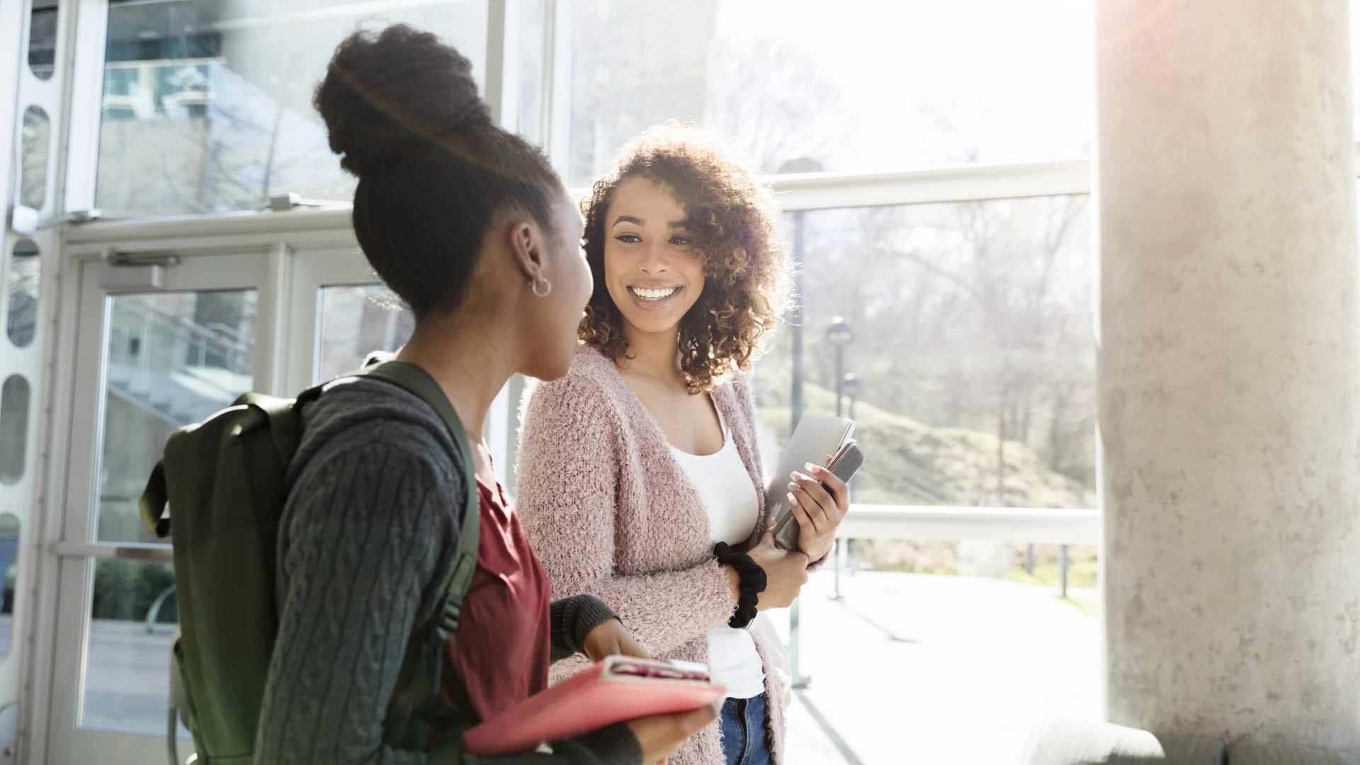 Estudantes universitárias conversando e sorrindo durante o intervalo de aulas no campus de uma instituição de ensino superior