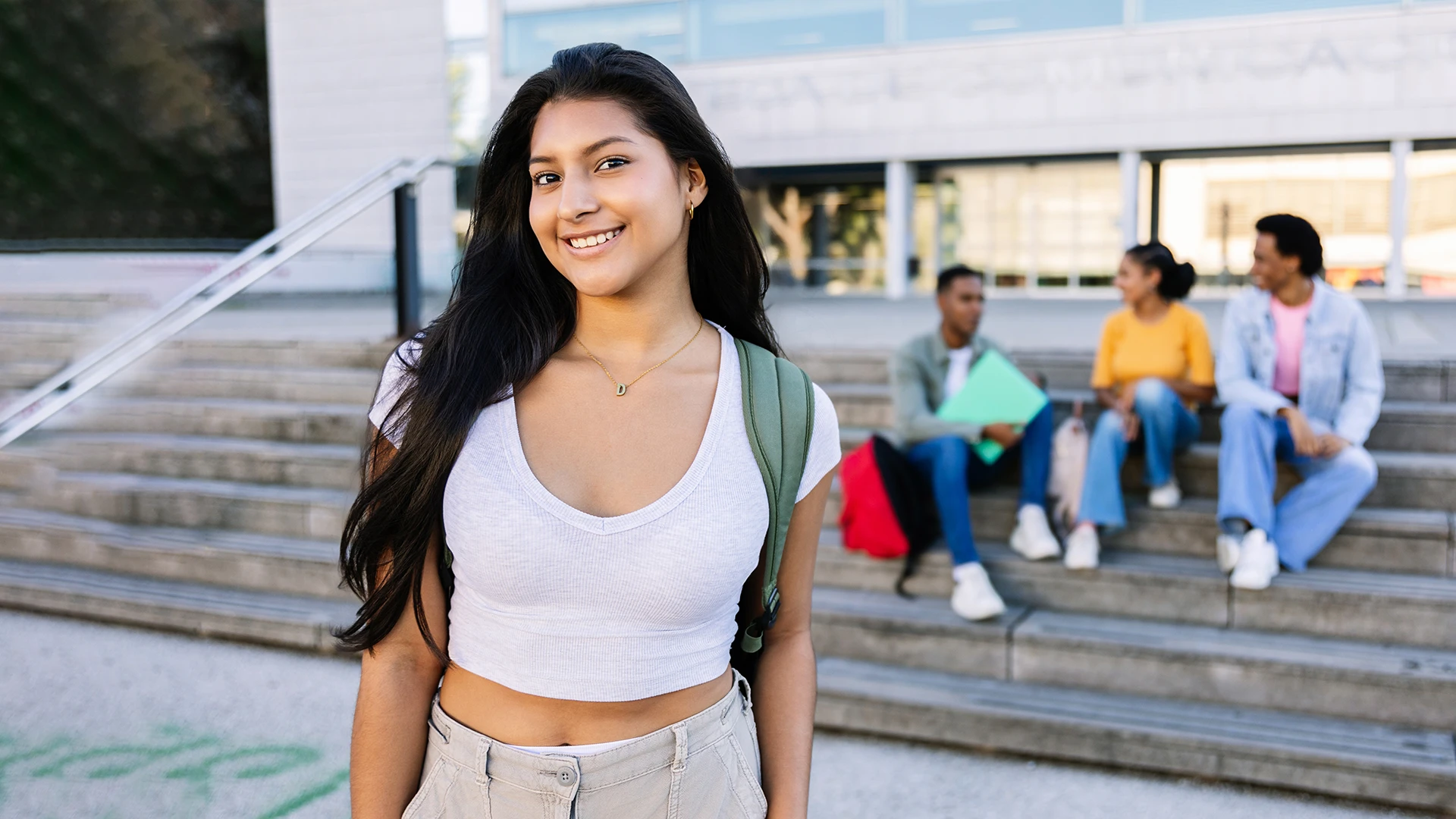 Estudante universitária sorridente com mochila em frente ao campus