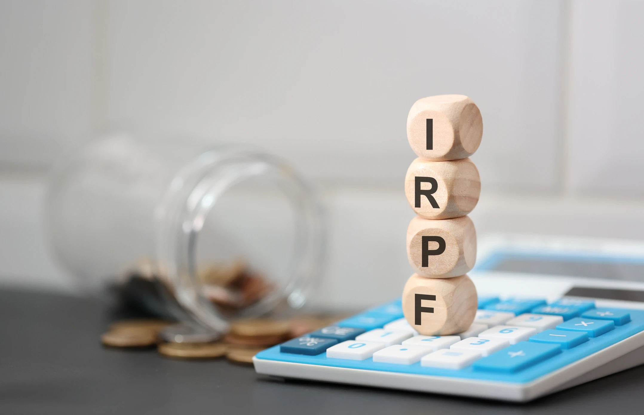 Dados de madeira empilhados com a sigla IRPF sobre uma calculadora