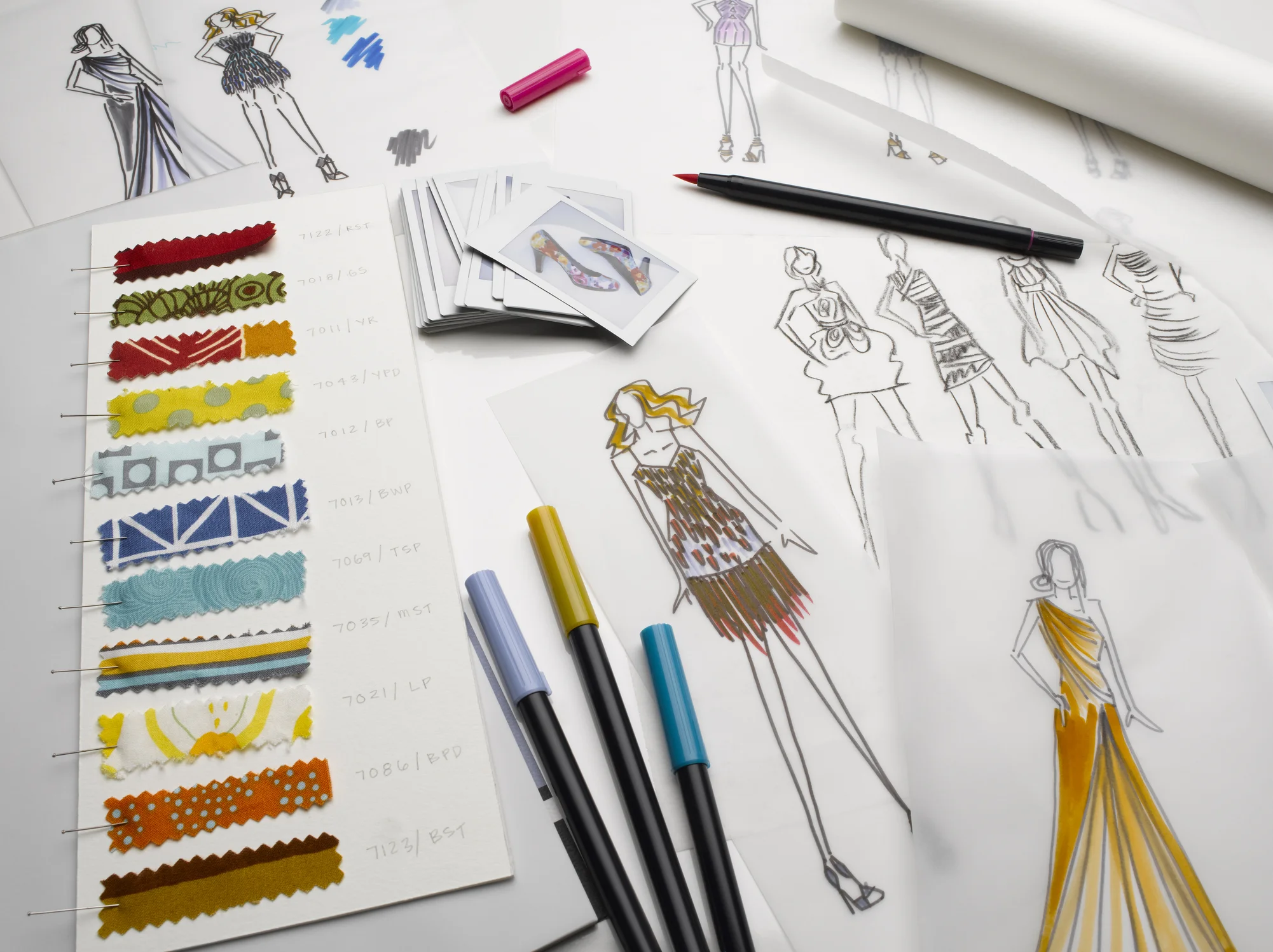 Processo criativo de design de moda com ilustrações de croquis, cartela de texturas têxteis e materiais de desenho profissional para estilistas