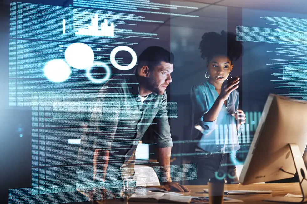 duas pessoas conversando em frente ao computador com hologramas tecnológicos por cima