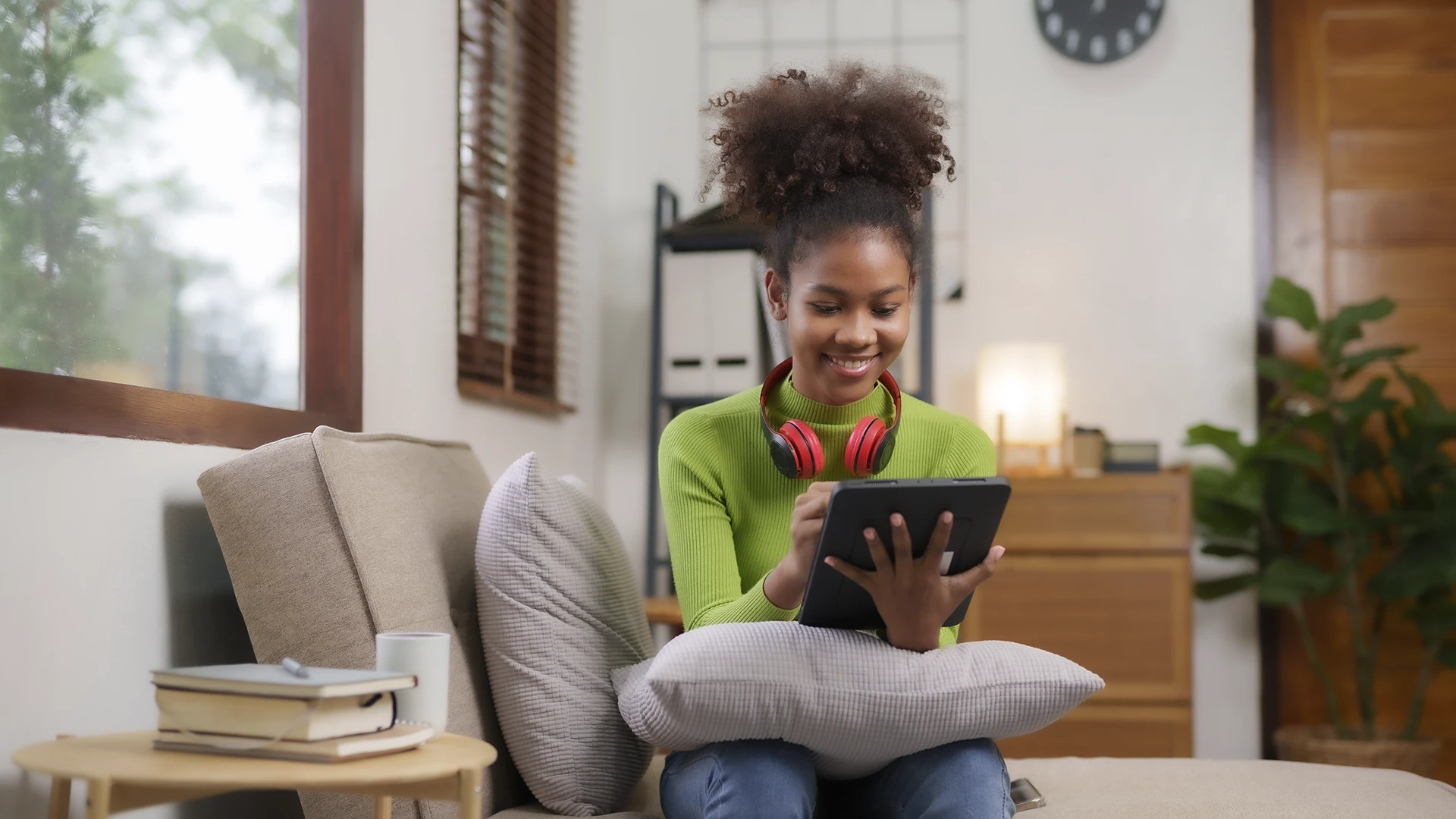Estudante jovem sorridente usando tablet para estudar em casa sentada no sofá