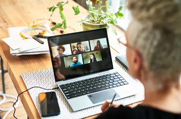 Pessoa participando de uma reunião virtual em um laptop em um ambiente de home office