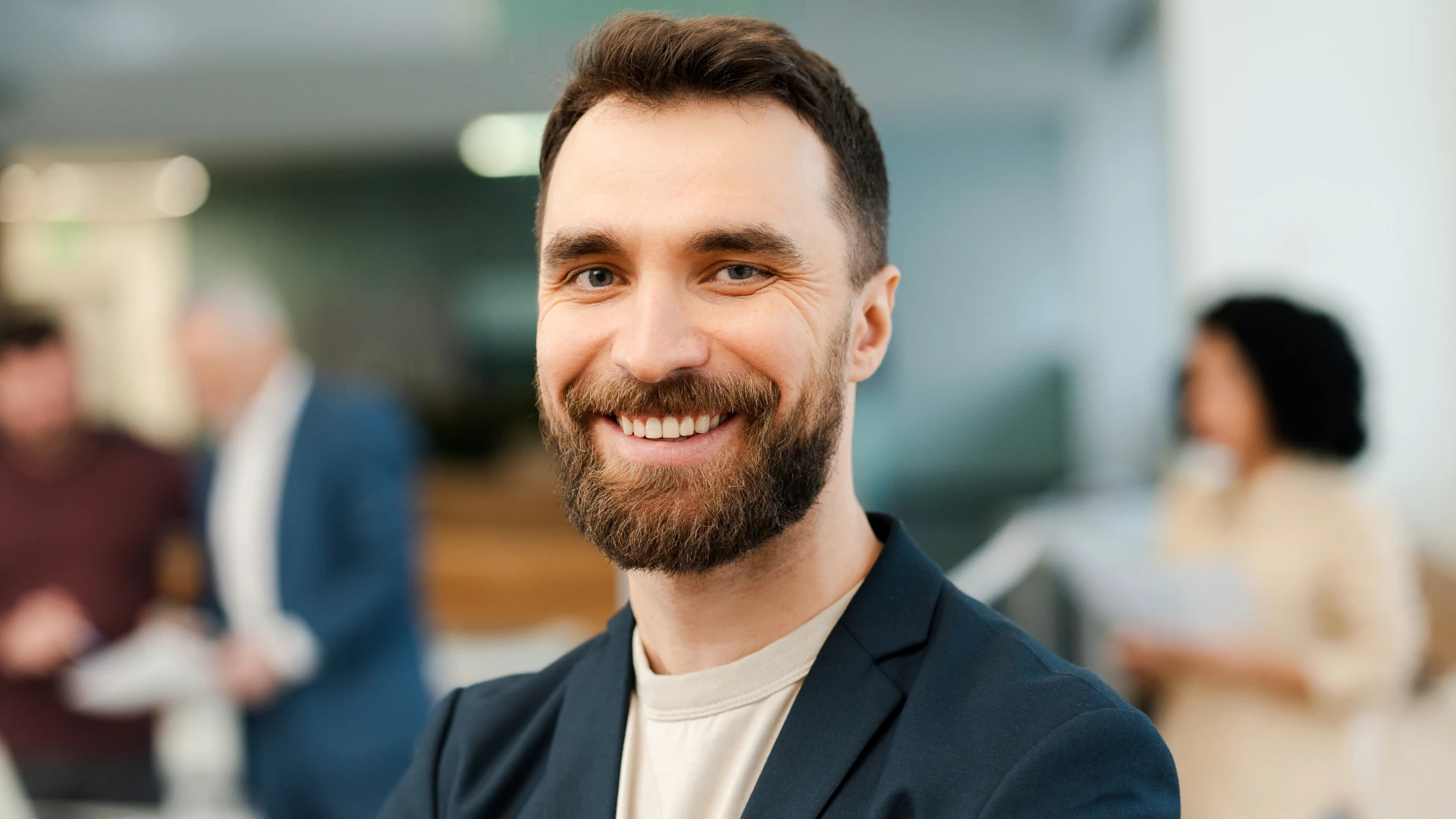 Retrato de um profissional sorridente em ambiente corporativo moderno com equipe ao fundo