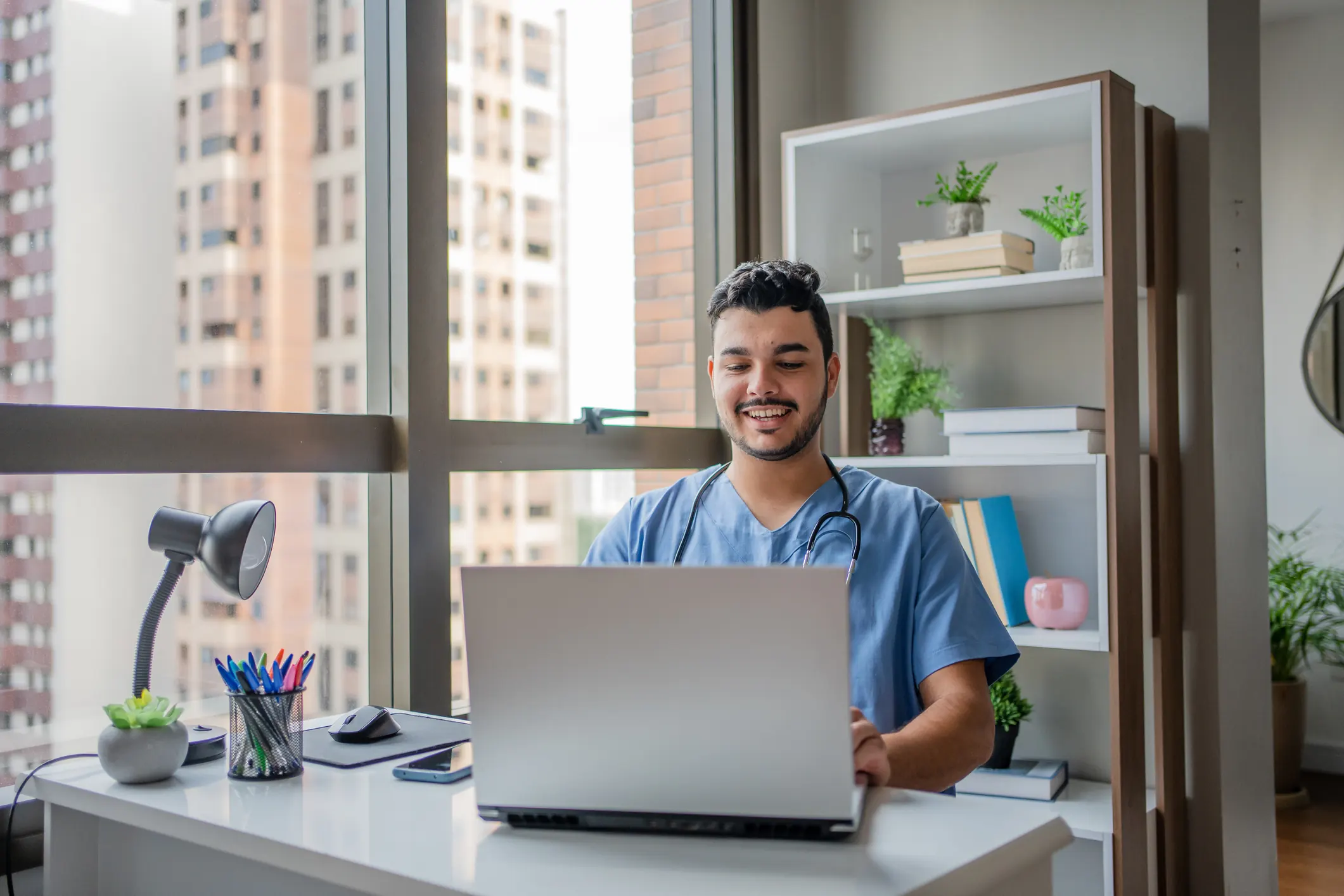 Estudante de medicina utilizando laptop para estudos ou telemedicina em um ambiente de trabalho confortável e moderno