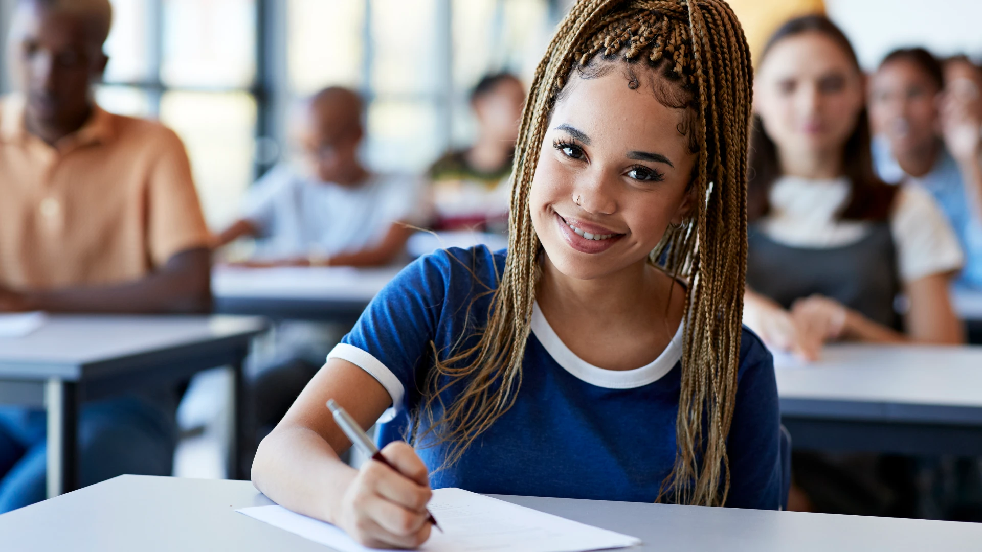 Estudante universitária focada e sorridente participando de uma aula em ambiente de ensino superior