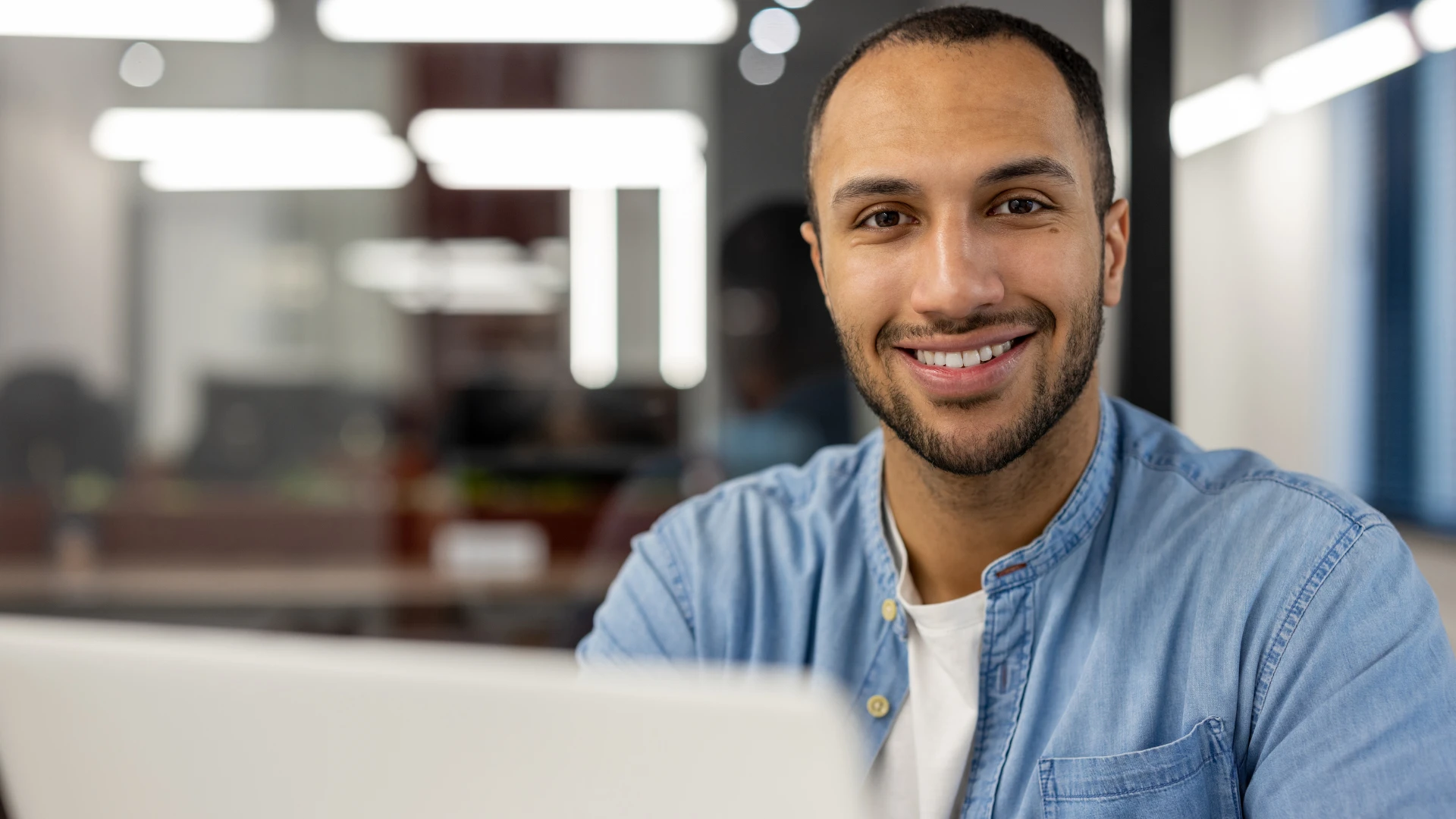 Homem sorridente trabalhando em um computador em um ambiente de escritório moderno