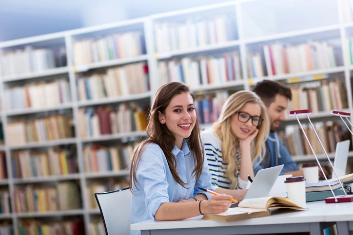 Estudantes universitários sorridentes estudando juntos em uma biblioteca