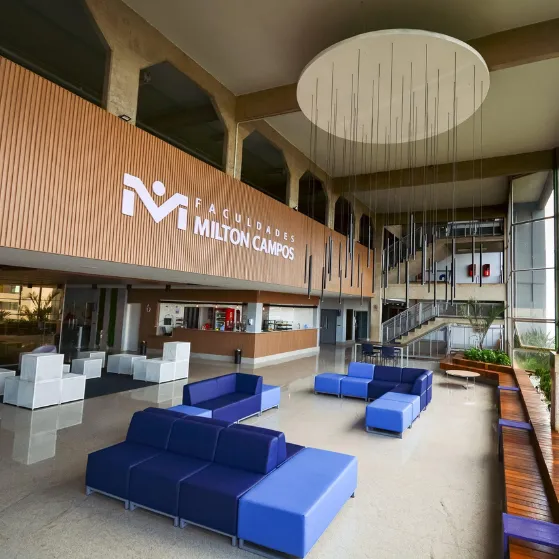 Área de convivência interna das Faculdades Milton Campos com sofás e decoração moderna