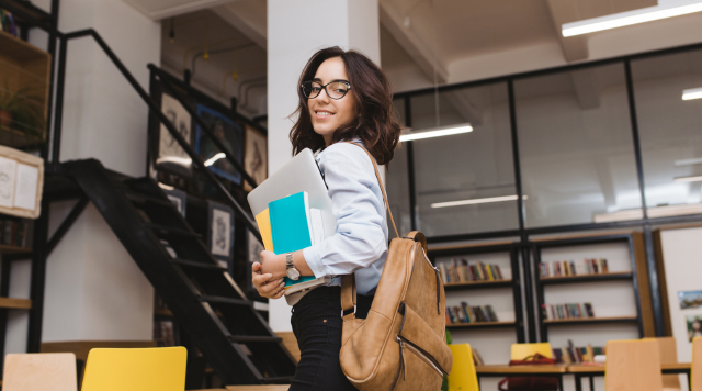 Estudante universitária preparada para os estudos com livros e notebook em um ambiente acadêmico moderno e inspirador para o aprendizado
