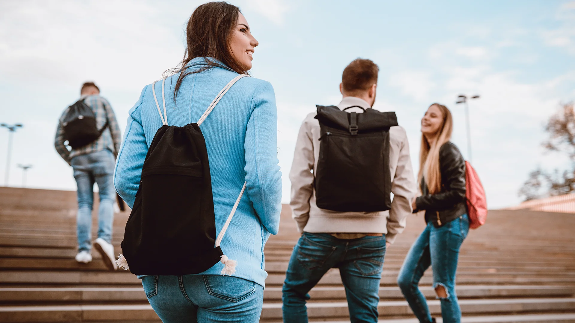 Grupo de estudantes universitários subindo escadaria de campus com mochilas
