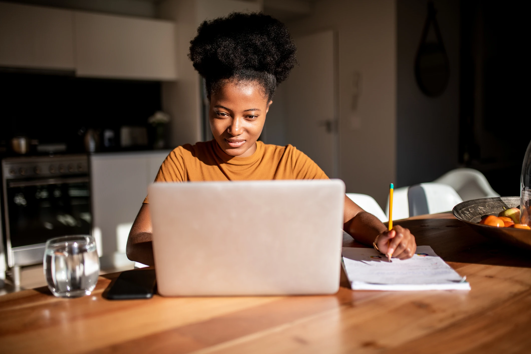 Estudante negra focada assistindo aula online em seu laptop na mesa da cozinha