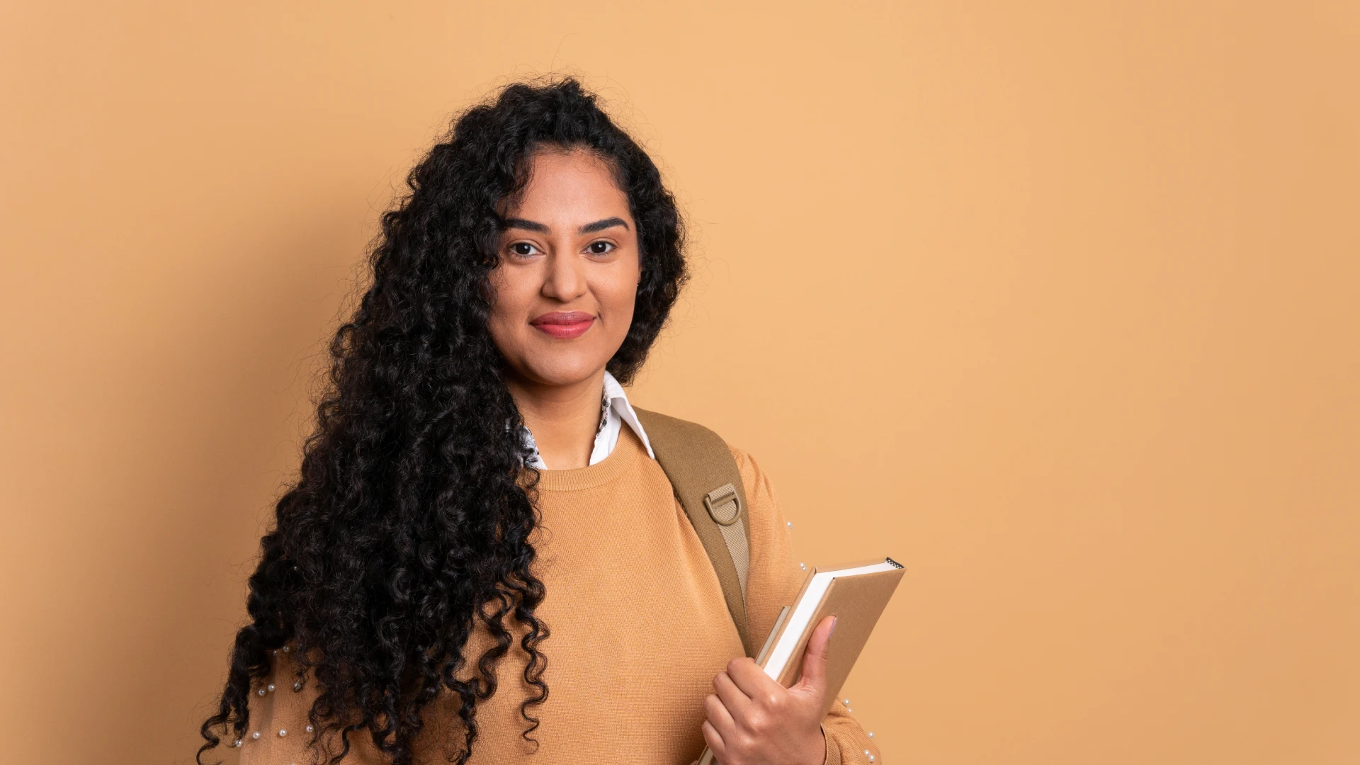 Estudante universitária sorridente segurando livros, pronta para as aulas em um ambiente educacional moderno