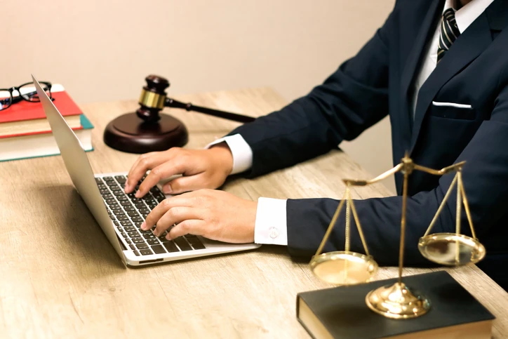 Advogado trabalhando em um laptop com martelo de juiz e balança da justiça na mesa