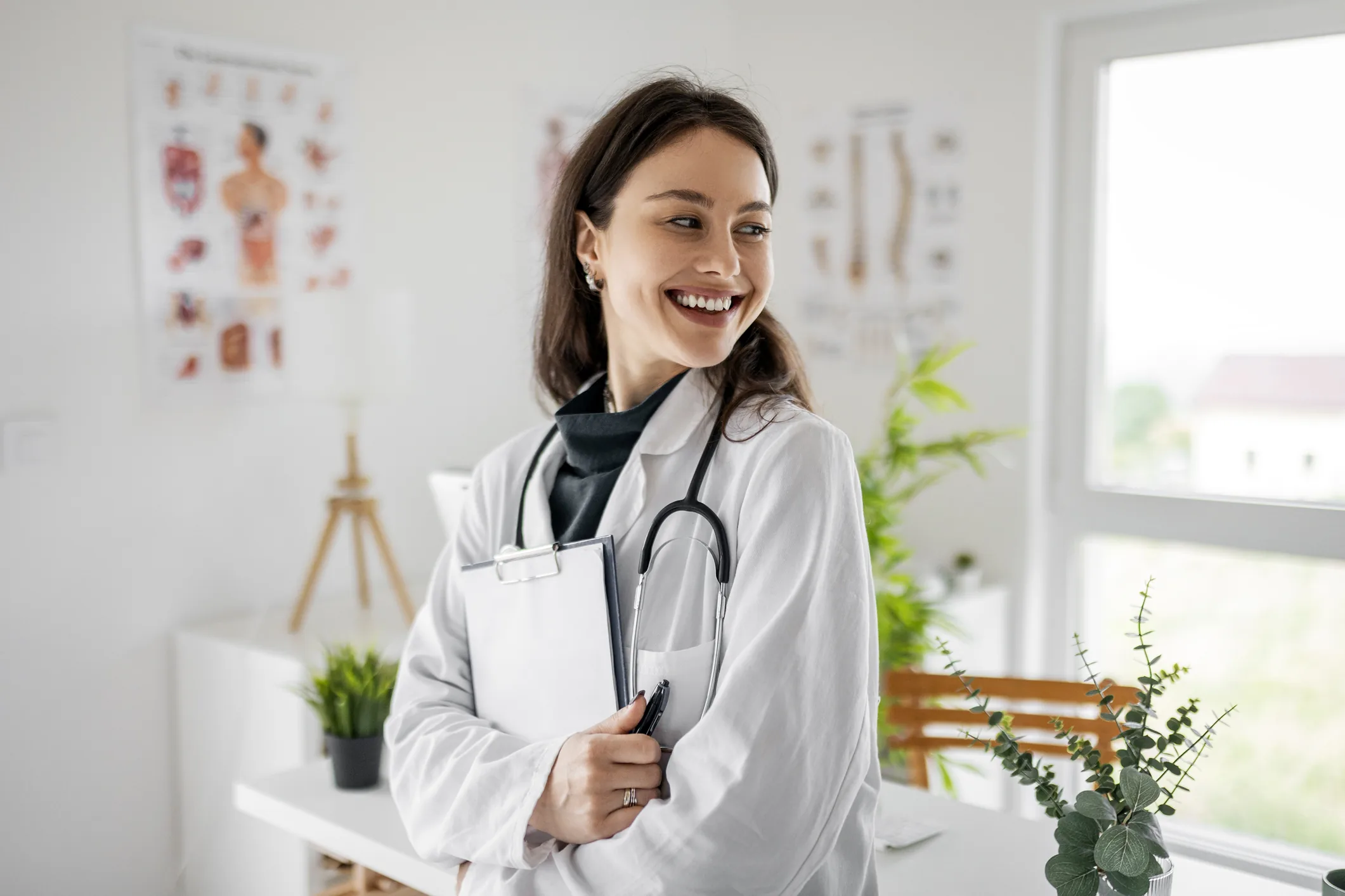 Médica profissional sorrindo em um consultório médico moderno com equipamentos de saúde ao fundo