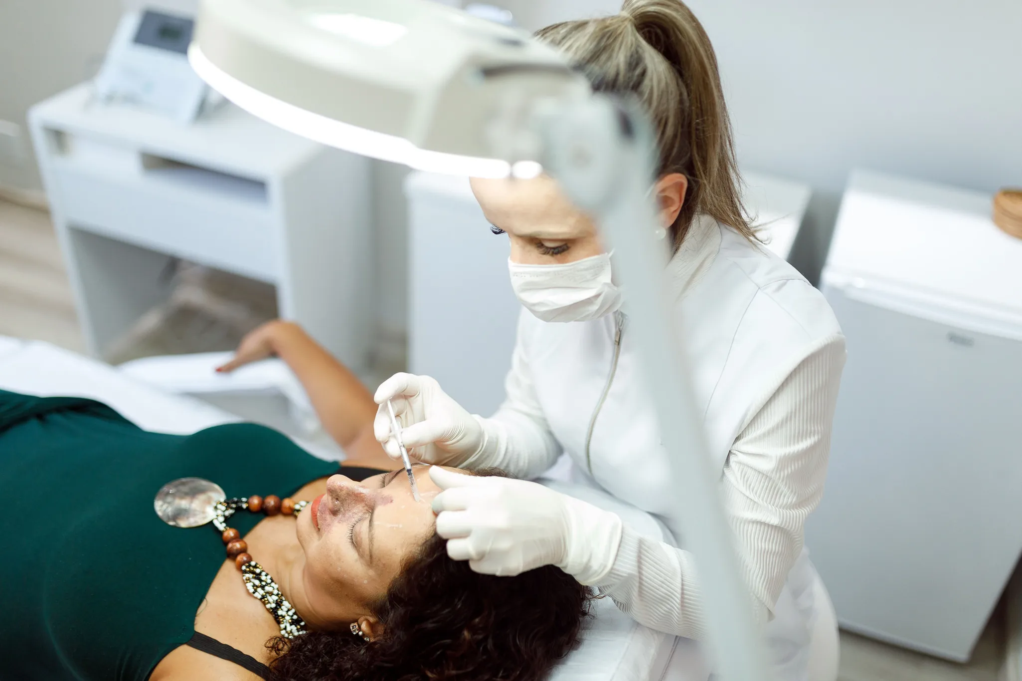 Profissional de estética realizando aplicação de botox na testa de uma paciente em clínica