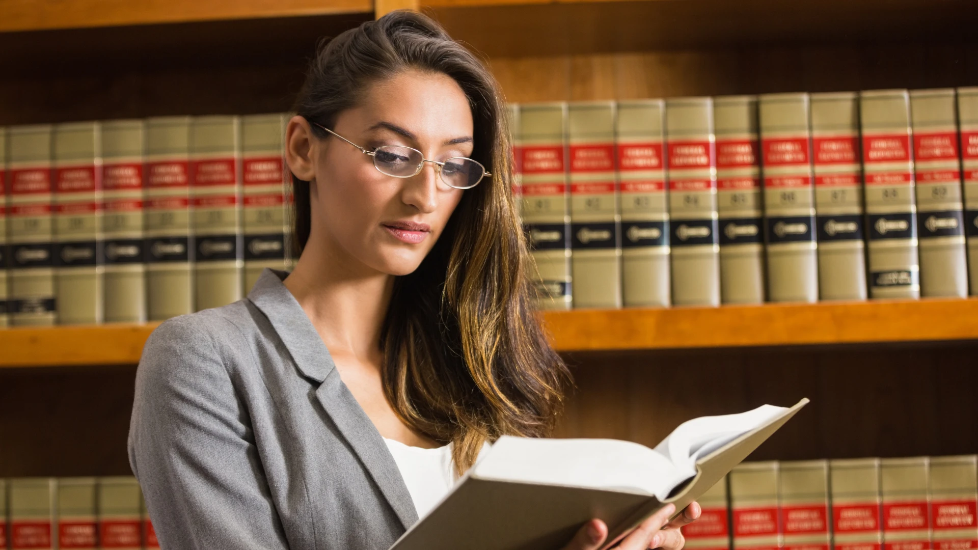 Advogada estudando livros jurídicos em uma biblioteca de direito.