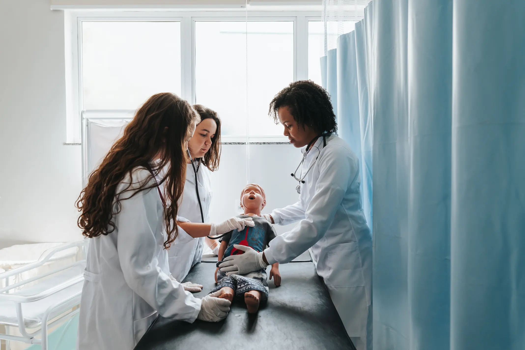 Estudantes de medicina praticando atendimento pediátrico em manequim de simulação realística