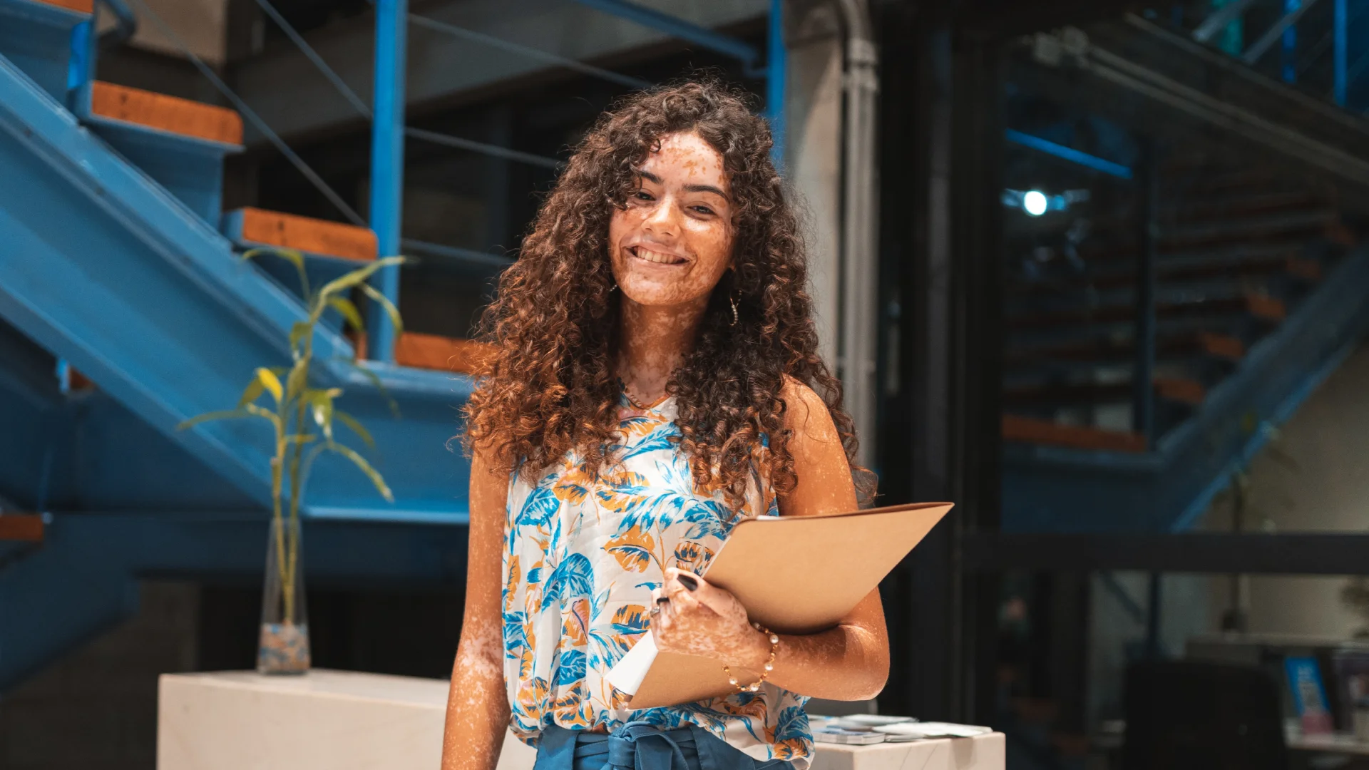 Estudante universitária sorridente com vitiligo em um campus de faculdade moderno para representar inclusão e educação